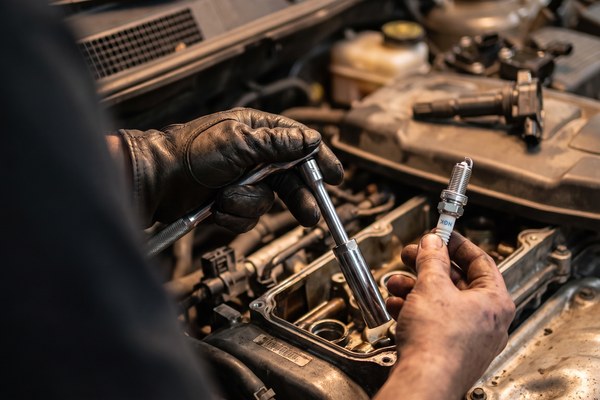 Mechanik z nasadką do świec i nową świecą zapłonową nad silnikiem – dobór cewki SAE i Napf